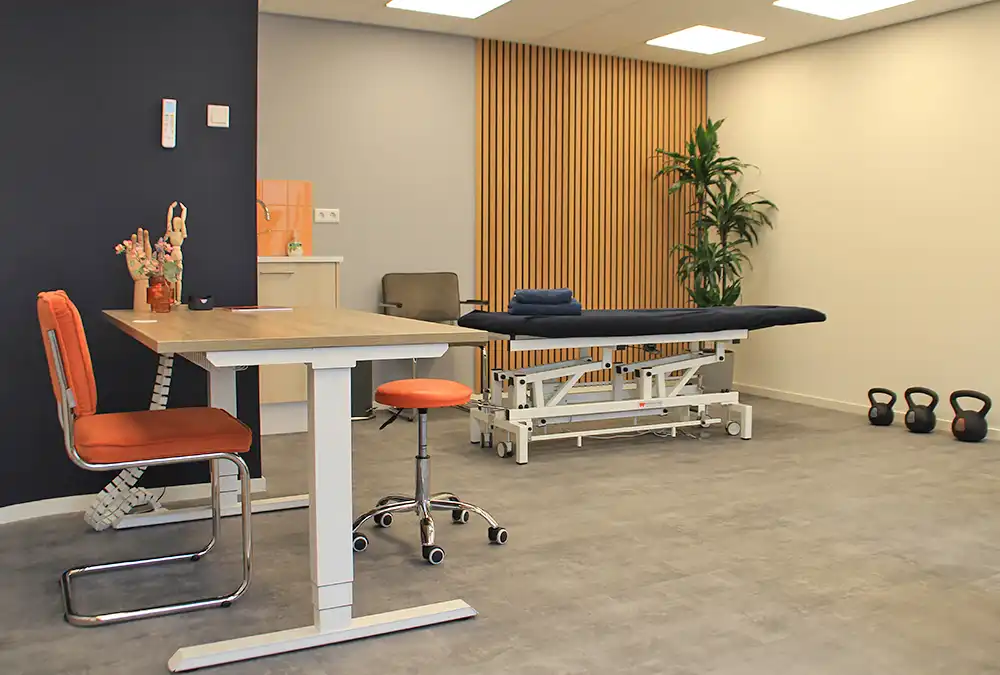 Praktijkruimte van Wey Gezondheidscentrum met ligstoel en tafel met stoelen.