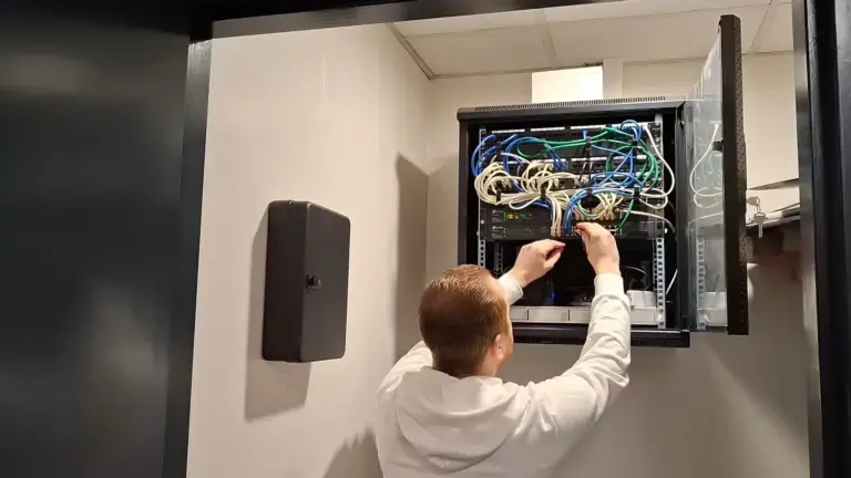 Mannelijke techneut die systemen controleert bij een technische kast, een voorbeeld van deskundig beheer en serverbeheer door ons ICT bedrijf uit Gouda.