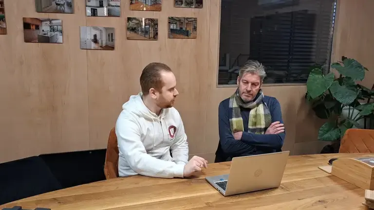 Consultant en klant in gesprek tijdens een ICT‑adviesgesprek, met laptop op tafel. Professionele ondersteuning door ICT bedrijf uit Gouda.